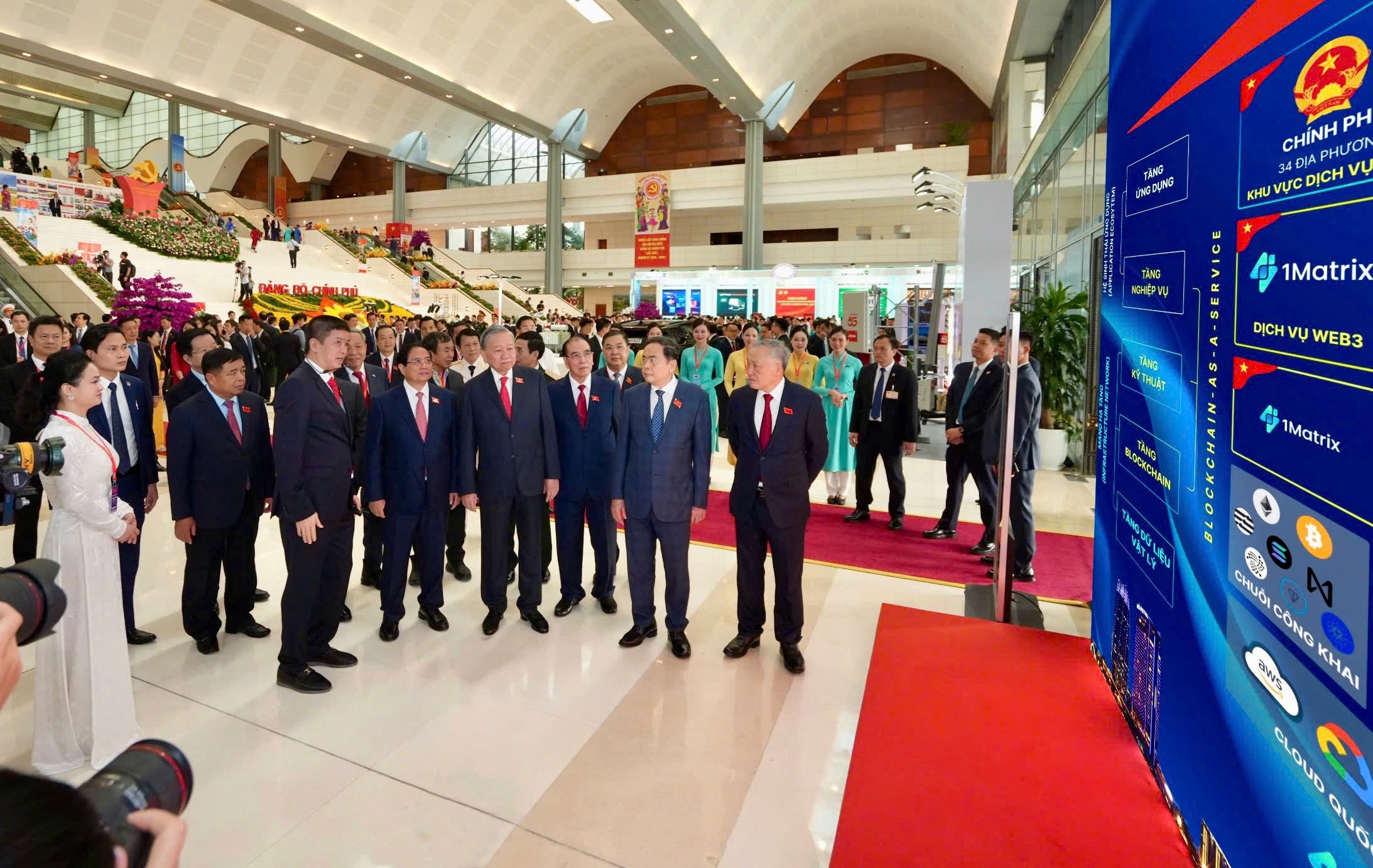 Tổng Bí thư Tô Lâm thăm khu vực trưng bày và nghe ông Phan Đức Trung chia sẻ về Mạng Dịch vụ Đa chuỗi Blockchain Việt Nam (VBSN) (Ảnh: VBA)